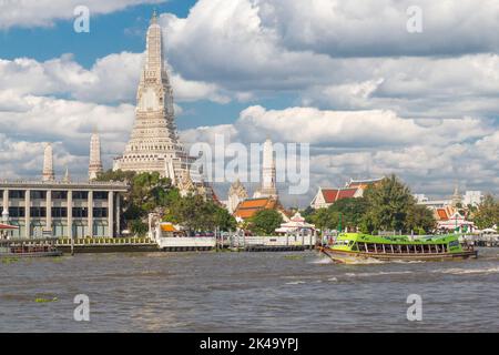 Bangkok, Tailandia. Mattina barca fluviale sul fiume Chao Phraya prende pendolari a lavorare. Il Wat Arun tempio in background. Foto Stock