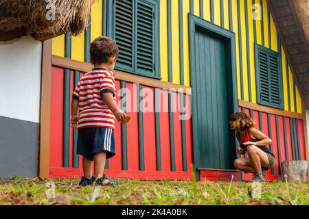 Madre e figlio giocano in una tradizionale casa di Madeiran nella foresta di Caldeirao Verde, Santana. Foto Stock