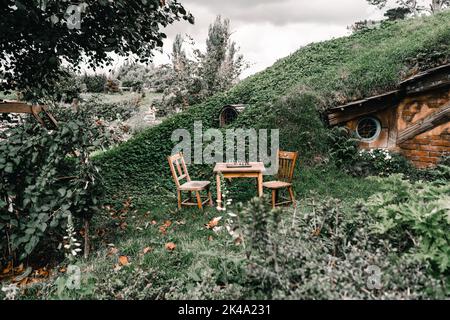 vecchie sedie di legno e tavolo con scacchiera e pezzi disposti ordinatamente sulla terrazza di casa di legno nascosto all'interno della foresta terra, monte maunganui, nuovo Foto Stock