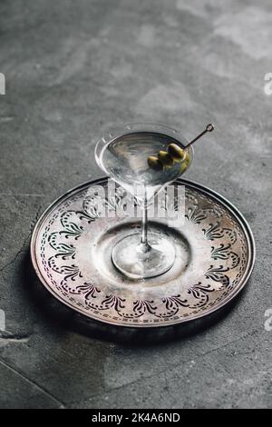 olive in martini su vassoio circolare grigio argento su pavimento in cemento Foto Stock