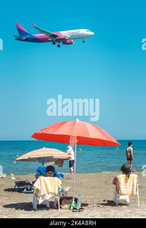 Larnaca, Cipro - 17 settembre 2022: Persone che riposano alla spiaggia di Mackenzie e atterrano Airbus A320-232 della compagnia aerea Wizz Air Foto Stock