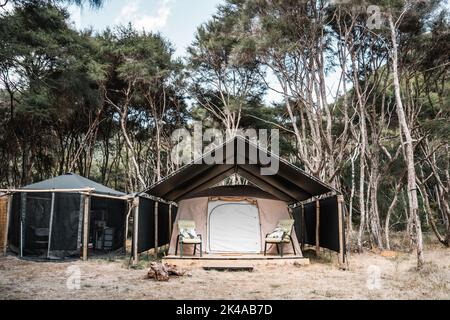 cucina all'interno di una tenda di canne e corde accanto alla stanza tenda con sedie e cuscini sulla terrazza in mezzo alla foresta e la natura Foto Stock