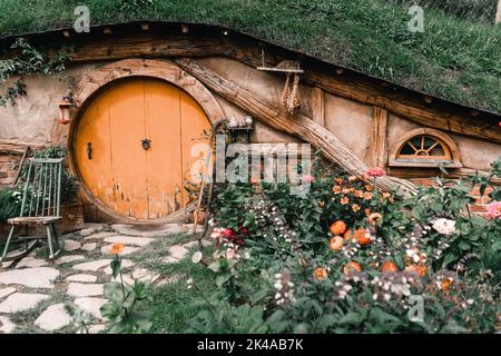 facciata di casa in legno con porte di legno rotonde e finestre costruite all'interno della terra di montagna, il monte maunganui, nuova zelanda Foto Stock