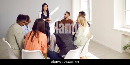 Diverse persone sedute in cerchio prendono parte alla sessione di terapia di gruppo alla riunione di psicoterapia. Foto Stock
