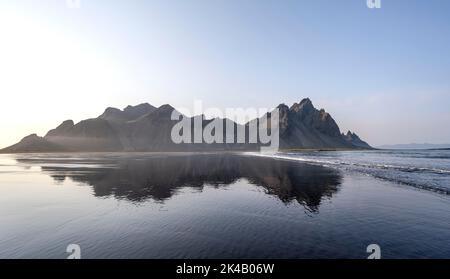 Spiaggia di lava nera, spiaggia sabbiosa e mare, montagne Klatindur riflesso in acqua, Eystrahorn e Kambhorn, promontorio Stokksnes, catena montuosa Foto Stock