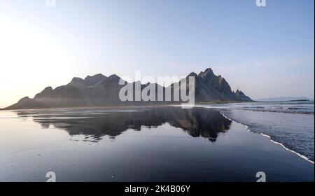 Spiaggia di lava nera, spiaggia sabbiosa e mare, montagne Klatindur riflesso in acqua, Eystrahorn e Kambhorn, promontorio Stokksnes, catena montuosa Foto Stock