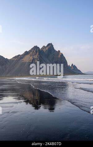 Spiaggia di lava nera, spiaggia sabbiosa e mare, montagne Klatindur riflesso in acqua, Eystrahorn e Kambhorn, promontorio Stokksnes, catena montuosa Foto Stock