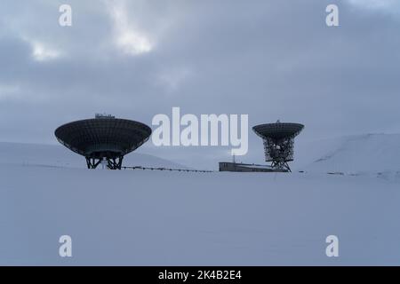 Grande antenna parabolica per la ricerca scientifica e spaziale al di fuori di Longyearbyen nel paesaggio invernale innevato, Svalbard Foto Stock