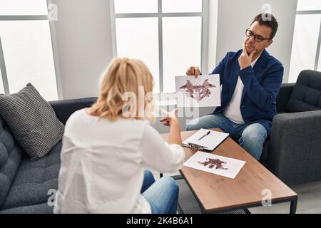 Uomo e donna di mezza età psychologist e paziente che fanno rorschach test al centro psicologico Foto Stock