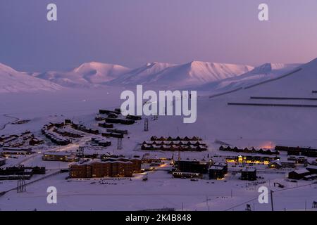 Renne di fronte a case residenziali colorate su palafitte in una fredda giornata invernale a Longyearbyen, Svalbard Foto Stock