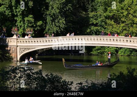 Una gondola passa sotto il Bow Bridge a Central Park, New York. Il ponte di Bow si estende sul lago che collega Bethesda Terrace al Ramble Foto Stock