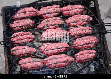 Il processo di cottura . I kebab di lula crudi sono fritti sulla griglia. Barbecue estivo per picnic Foto Stock