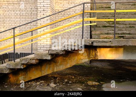 vecchi gradini in cemento con ringhiere in metallo giallo che conducono all'edificio. Foto Stock