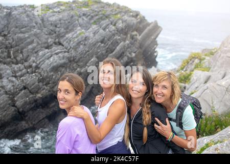 Un ritratto di donne caucasiche sorridenti alla macchina fotografica, su una spiaggia rocciosa Foto Stock
