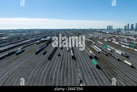 Un'alta vista aerea sopra un vasto cantiere ferroviario merci, visto in una chiara giornata di cielo blu. Foto Stock