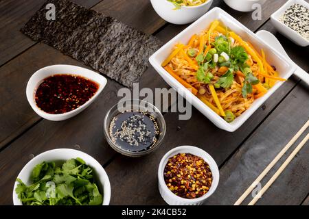 Vista dall'alto del wok asiatico, spaghetti saltati con bacchette e condimenti in legno Foto Stock