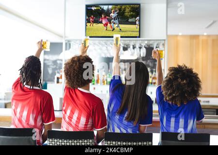 Diversi amici al bar guardando la tv con partita di calcio sullo schermo Foto Stock