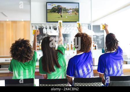 Diversi amici al bar guardando la tv con partita di calcio sullo schermo Foto Stock