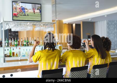 Diversi amici al bar guardando la tv con partita di calcio sullo schermo Foto Stock