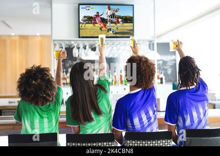 Diversi amici al bar guardando la tv con partita di calcio sullo schermo Foto Stock