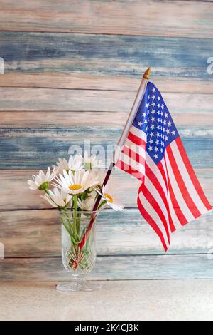 rustica vita morta di semplici margherite bianche e una bandiera americana, su uno sfondo di legno fienile blu Foto Stock