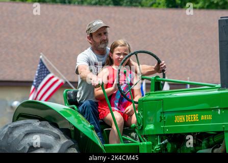 Eau Claire MI USA, 4 2022 luglio; la giovane ragazza si sposta su un trattore con papà, in una parata il 4th luglio Foto Stock