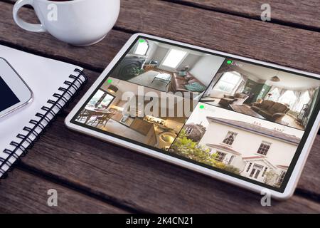 Tablet con vista della casa da telecamere di sicurezza su schermo sdraiato su un tavolo di legno. Sicurezza, sicurezza, sorveglianza e interfaccia digitale. Foto Stock