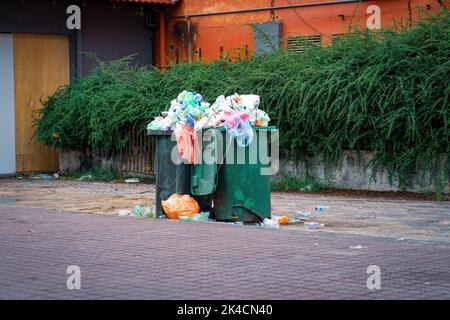 Una spazzatura traboccante può o spazzatura può con vari contenitori di plastica nel parco pubblico durante il fine settimana Foto Stock