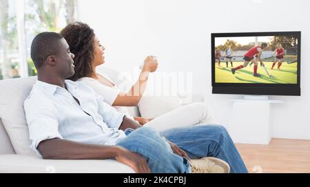 Giovane seduto sul divano insieme guardando la tv a casa nel soggiorno Foto Stock