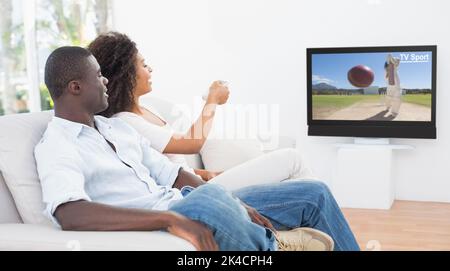 Giovane seduto sul divano insieme guardando la tv a casa nel soggiorno Foto Stock