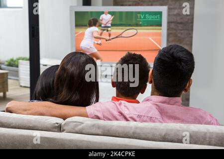 Vista posteriore di famiglia felice guardando la tv sul divano Foto Stock