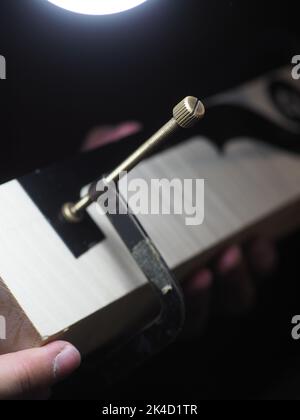 Primo piano di un maestro artigiano professionista luziatore scrupoloso lavoro dettagliato su violino in legno in un laboratorio. Foto Stock