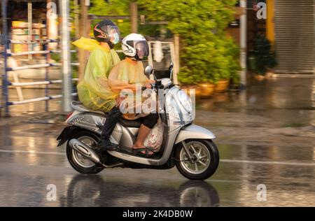 SAMUT PRAKAN, THAILANDIA, 21 2022 SETTEMBRE, coppia in impermeabile guidare in forte pioggia Foto Stock