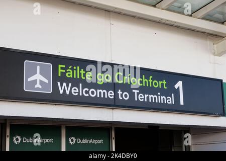 Cartello bilingue "Benvenuti al Terminal 1" in irlandese e inglese all'ingresso dell'aeroporto di Dublino. Foto Stock