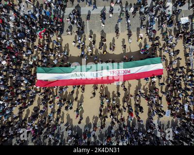 (I redattori notano l'immagine presa da un drone) le persone si radunano fuori dal municipio di San Francisco con un grande banner tat dice 'Donna, vita, libertà'. Dopo la morte della ragazza iraniana Mahsa Amini, proteste e manifestazioni per sostenere l'Iran sono avvenute in tutto il mondo. A San Francisco, migliaia di persone si radunano e marciano per strada con foto di Mahsa Amini, striscioni, cartelloni e la bandiera dell'Iran. Le persone che aderiscono al rally pensano che tutti debbano sostenere l'iraniano e urlano "Donna, vita, libertà” durante il rally. Foto Stock