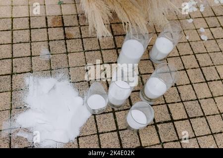 Un portacandele di vetro rotto sulla piastrella vicino all'arco di nozze. Accessori per matrimoni, gioielli. Foto Stock