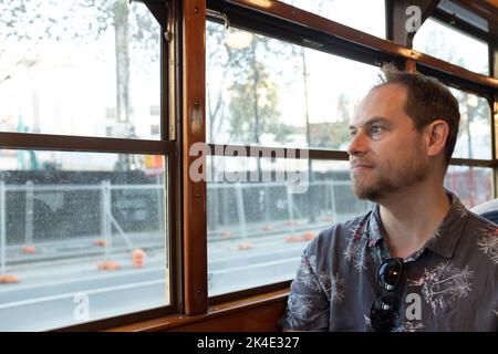 Un uomo seduto in un famoso tram storico di Melbourne W Class che guarda fuori dalla finestra Foto Stock