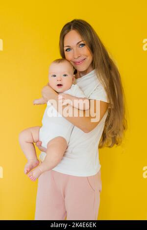 La madre amorevole si prende cura di un neonato a casa. Ritratto di una madre felice che tiene in braccio un figlio dolce. Foto Stock