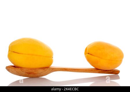 Due succulente albicocche di ananas con un cucchiaio di legno, primo piano, isolate su bianco. Foto Stock