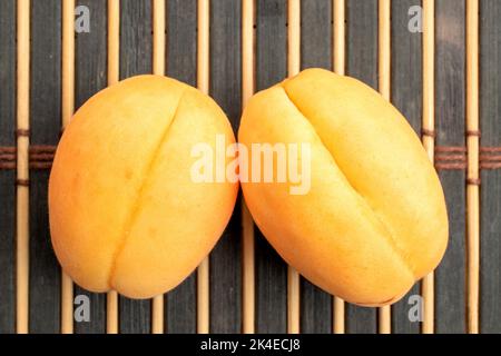 Due succose albicocche di ananas gialle su un tappeto di bambù, primo piano. Foto Stock