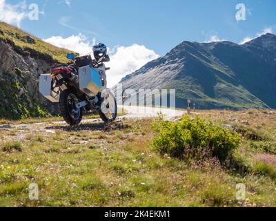 Una moto avventura con grandi casse in alluminio è parcheggiata presso un passo di montagna nelle alpi europee. Vista posteriore, vista ad angolo basso Foto Stock