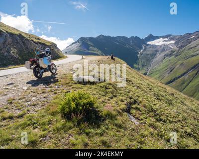 Una moto avventura con grandi casse in alluminio è parcheggiata presso un passo di montagna nelle alpi europee. Vista posteriore, vista ad angolo basso Foto Stock