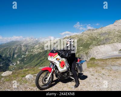 Un motociclista avventuroso in un passo di montagna nelle alpi Svizzere. Foto Stock
