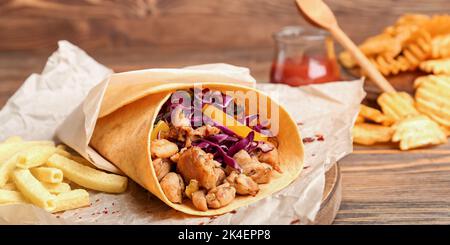 Gustoso kebab doner, patatine fritte e patatine fritte su sfondo di legno, primo piano Foto Stock