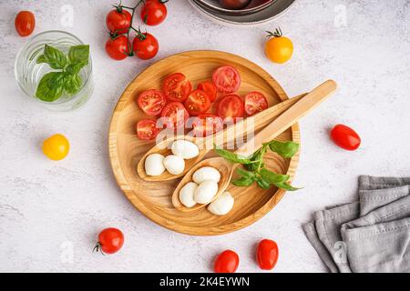 Piatto di legno con gustosa mozzarella e pomodori freschi su un tavolo leggero Foto Stock