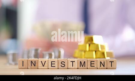 Pile di monete lingotti d'oro puro e investimento di iscrizione Foto Stock