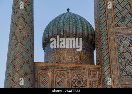 Sherdor Madrassa nel complesso del Registan al tramonto con belle piastrelle blu sul minareto e arco, Samarcanda Foto Stock