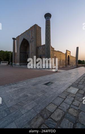 Sherdor Madrassa nel complesso del Registan al tramonto con belle piastrelle blu sul minareto e arco, Samarcanda Foto Stock