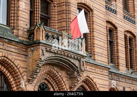 Bandiera polacca su un balcone dello storico edificio in mattoni rossi dell'ufficio postale Foto Stock