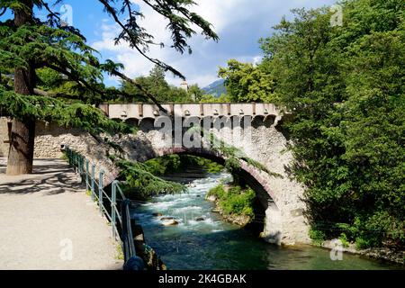 La pittoresca città mediterranea di Merano con un ponte in pietra ornato sul fiume verde smeraldo Passero (Italia, Trentino-Alto Adige, Alto Adige) Foto Stock